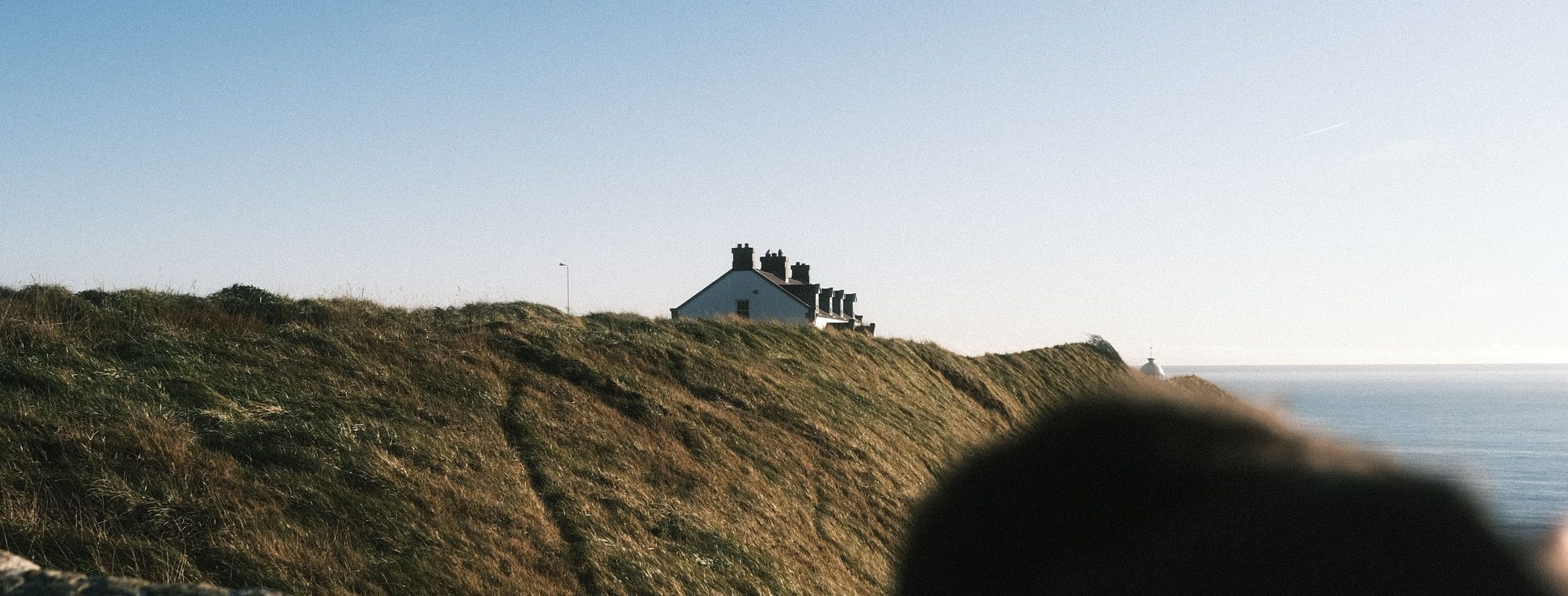 A cottage on a grassy Irish clifftop overlooking the sea