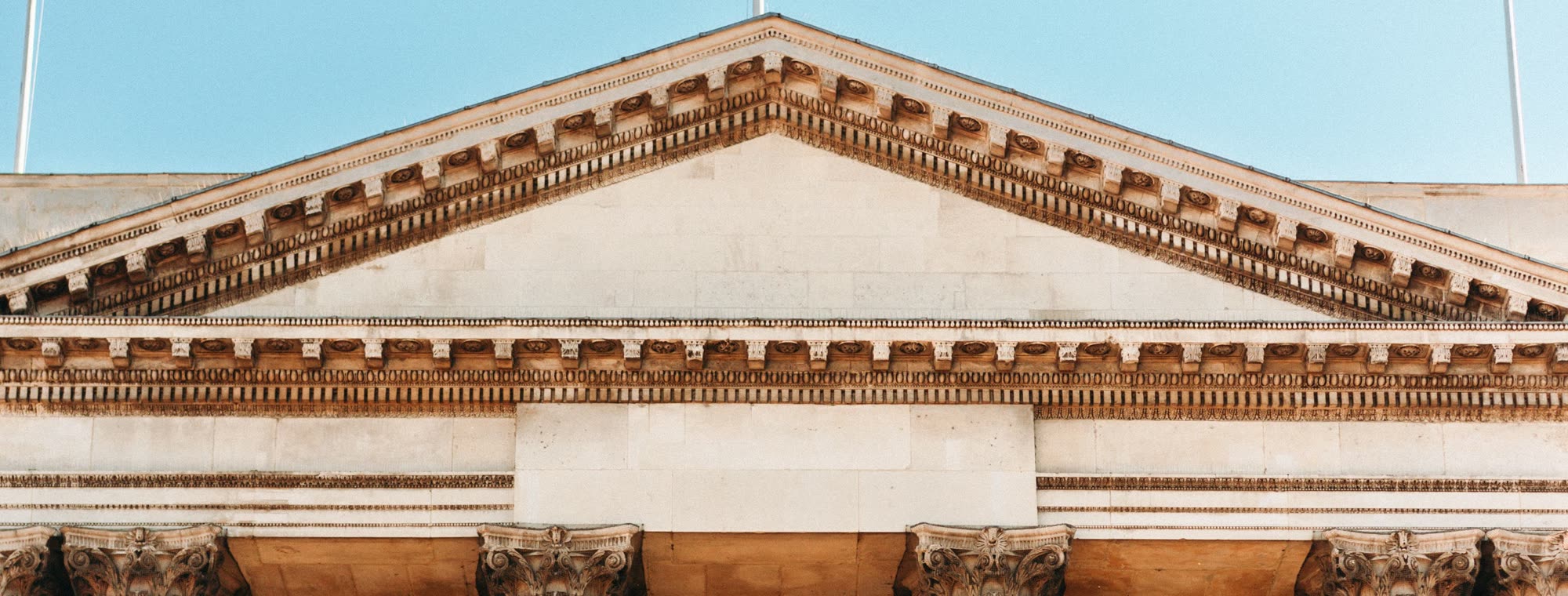 The carved stone pediment and columns of a Georgian public building in Dublin against a clear blue sky