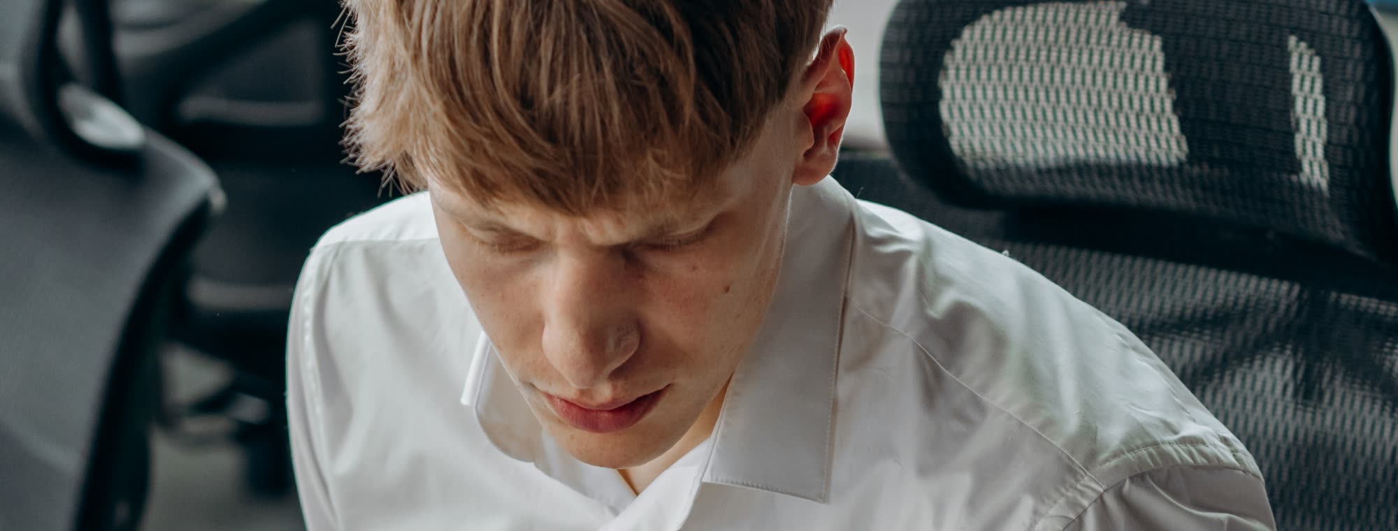 An employee in a white shirt looking down at paperwork on his desk